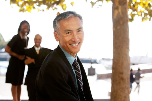 An asian looking business man with colleagues in the background