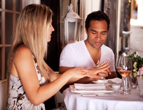 A man giving a woman a ring in an outdoor cafe in France, Europe