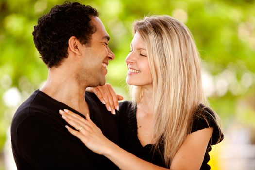 A happy couple smiling and looking at each other in a park