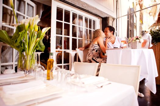 A romatic couple kissing in an outdoor restaurant