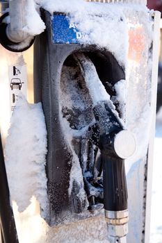 A gas pump frozen with ice and snow - frozen gas prices concept