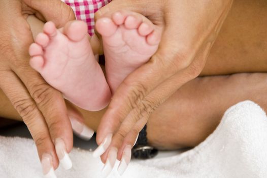 mommy holding baby's feet against white background