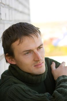 Portrait of the young man in a green sweater on an abstract background