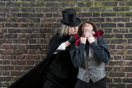 Fashion shot of woman  dressed as Jack the Ripper strangling man