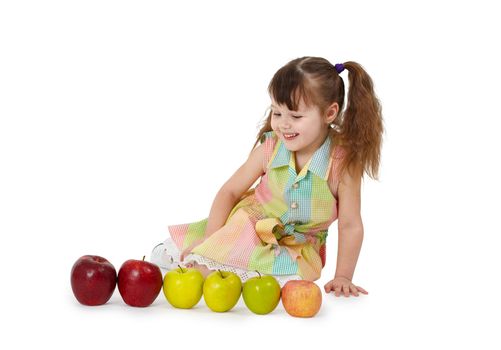 The little girl sits on a white background with apples