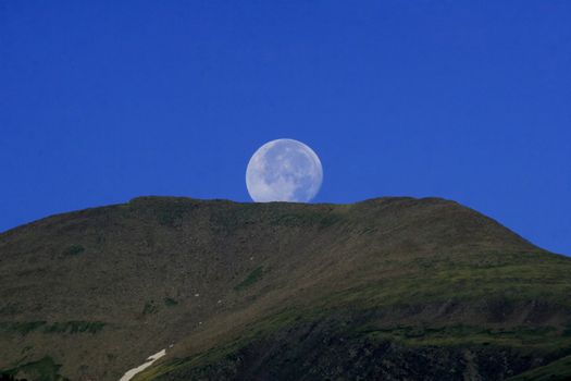 Morning full moon setting over mountaintop in the Colorado Rocky Mountains with copyspace