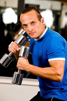 Strong man in health club curling a dumbbell