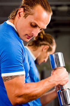 Strong man in health club curling a dumbbell