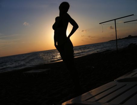 silhouette of beautiful woman at the seashore against tne sunset