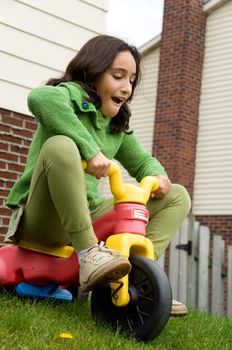 A girl going down a steep hill with her tricycle.