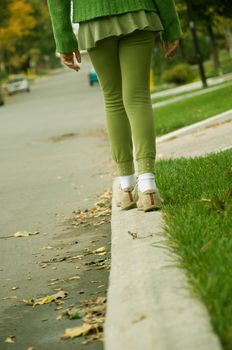 A girl balancing her self on the sidewalk.