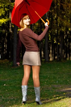 The young girl with a red umbrella in autumn park