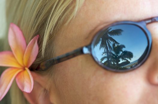 Woman Relaxing while Sunglasses Reflect Palm Trees and Shorline.