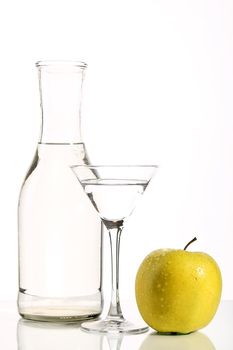 Bottle with transparent water, a glass and apples on a white background