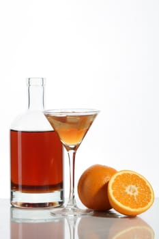 Bottle with an alcoholic drink, a glass and an orange on a white background