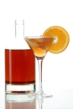 Bottle with an alcoholic drink, a glass and an orange on a white background