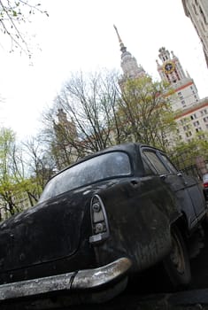 old car on a background of trees and high-rise building