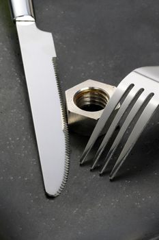 hex nut on a black plate with knife and fork