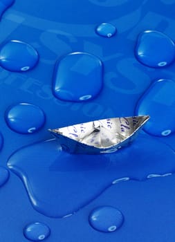 paper boat floating on water drops ,over blue background