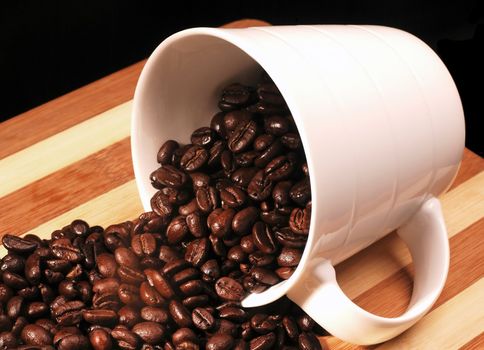 coffee beans on a cup  spilled on wood board