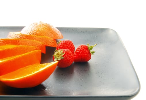 orange & strawberries on a plate on white background