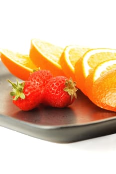 orange & strawberries on a plate on white background