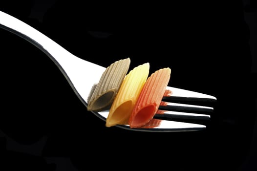 italian penne pasta on a fork on black background