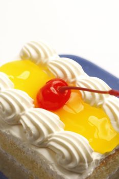 piece of lemon jelly cake with cherry on top on white background