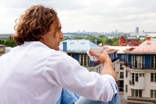 Caucasian man sitting with a cup coffee outdoors