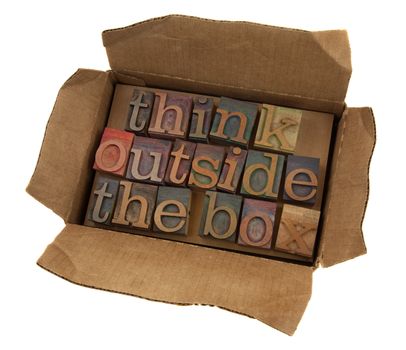 think outside the box concept, words  in vintage letterpress type  in open cardboard box, isolated on white