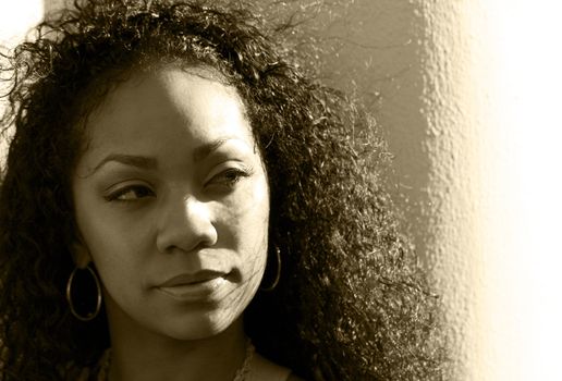 Dramatic portrait of a thoughtful young black woman with shadows in sepia tone