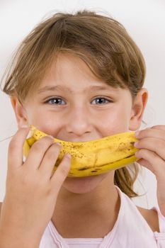 little girl eating banana and looking at the camera
