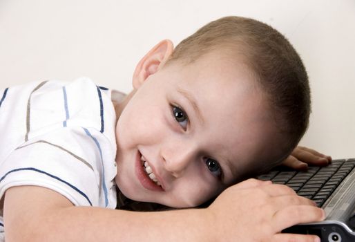 little boy lying on laptop looking at camera