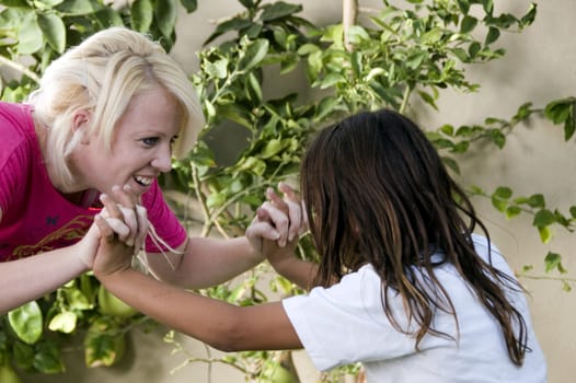 young boy fighting with blonde woman on natural background
