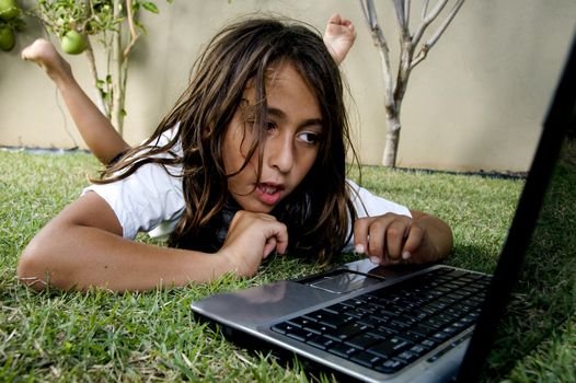 boy lying on grass working on laptop
