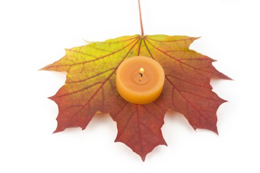 single autumn maple leaf with a tea light