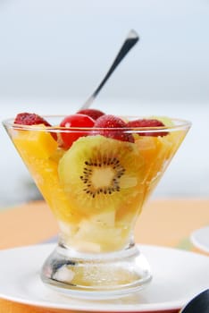 Fruit breakfast at the beach, with cherries, strawberries, peaches and kiwifruit.