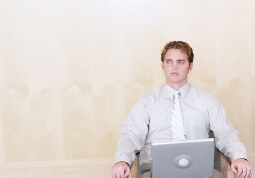 Businessman sitting in his desk chair with his laptop computer in front of him thinking about business solutions wearing business casual clothes