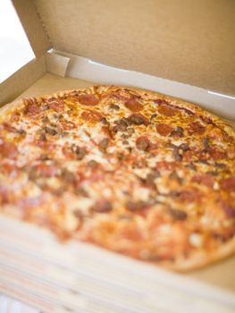 full pizza being shown with the lid open on a stock of four pizza boxes
