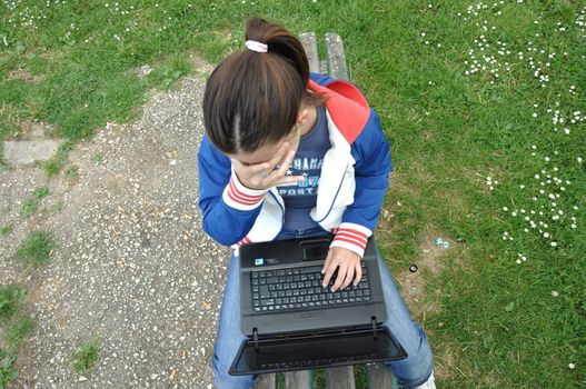 student uses a laptop in the park