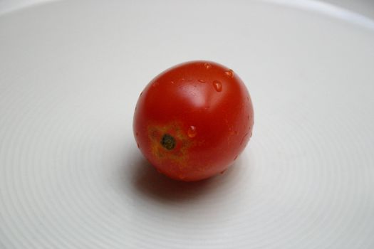 a tomato with water drops on a white dish
