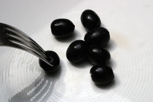 Six italian olives and one speared by a fork