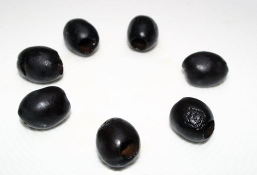 a circle of seven olives on white background