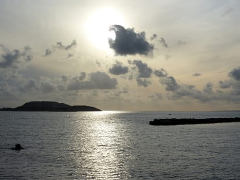 Two islands and sunlights reflecting on the quiet sea by cloudy sunset