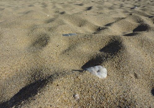 Sand of a beach with small grey stone in it