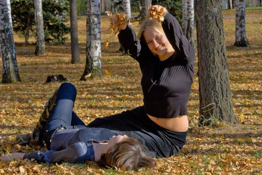 Two girlfriends in autumn park during a leaf fall