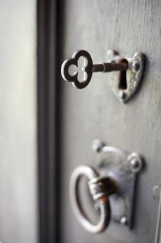 an metal key inserted into an old door pictured with a narrow depth of field