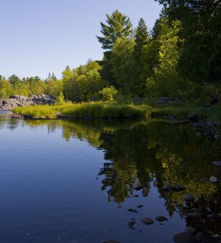 The still shoreline of the St. Louis river in northern Minnesota in green and blue
