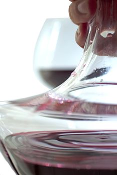 Decanter full of red wine over background with glass of red wine