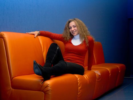 Portrait of the happy young girl sitting on a sofa